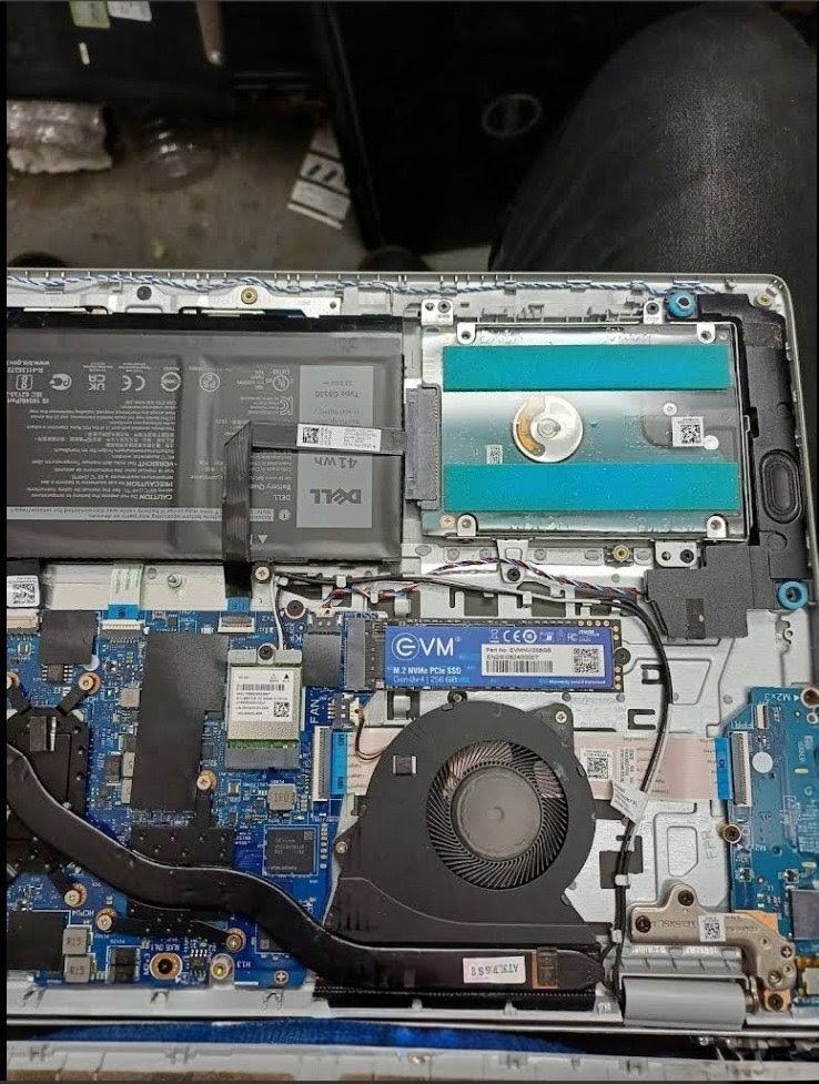 Dell laptop opened showing a newly fitted M.2 NVMe SSD beside the battery and fan